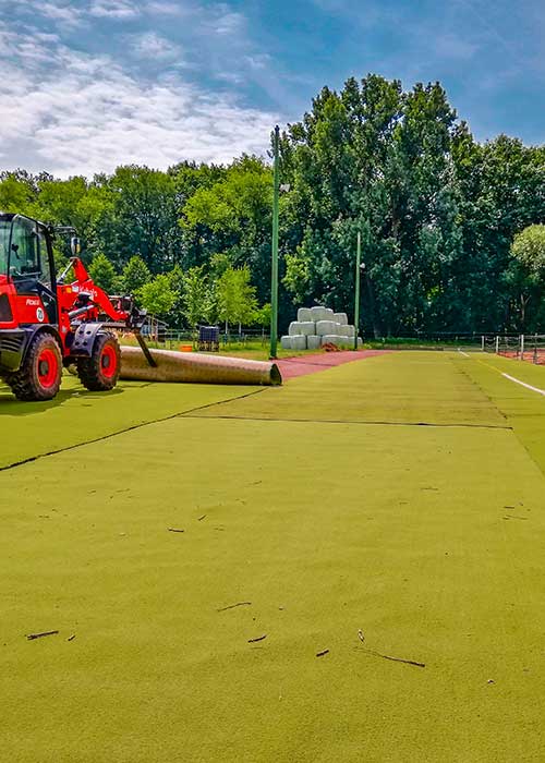 Traktor rollt Kunstrasenrolle aus 