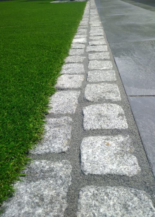 Übergang von Kunstrasen und Pflastersteine